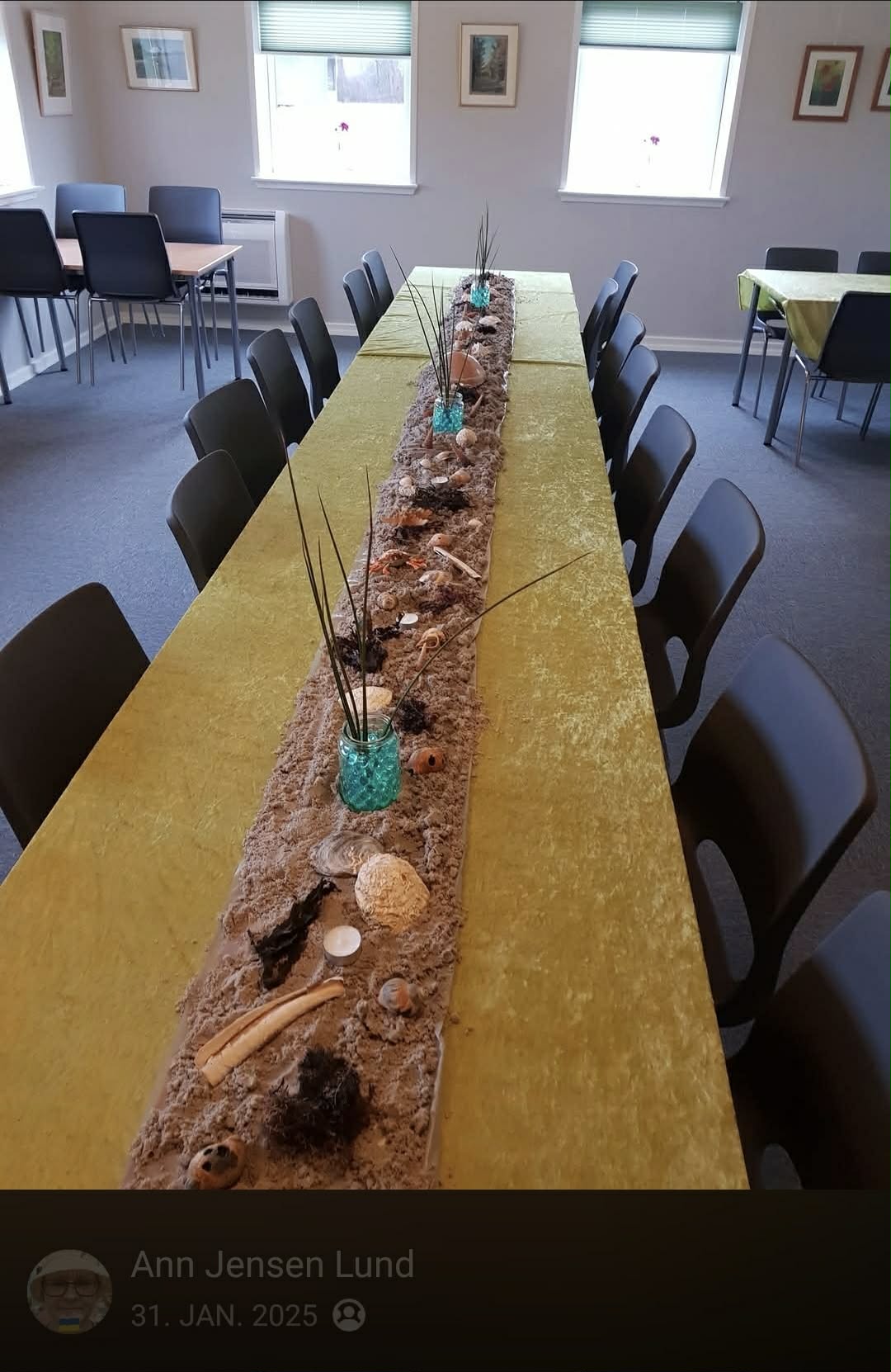 Langbord pyntet med strandtema — sand, muslingeskaller og strå
