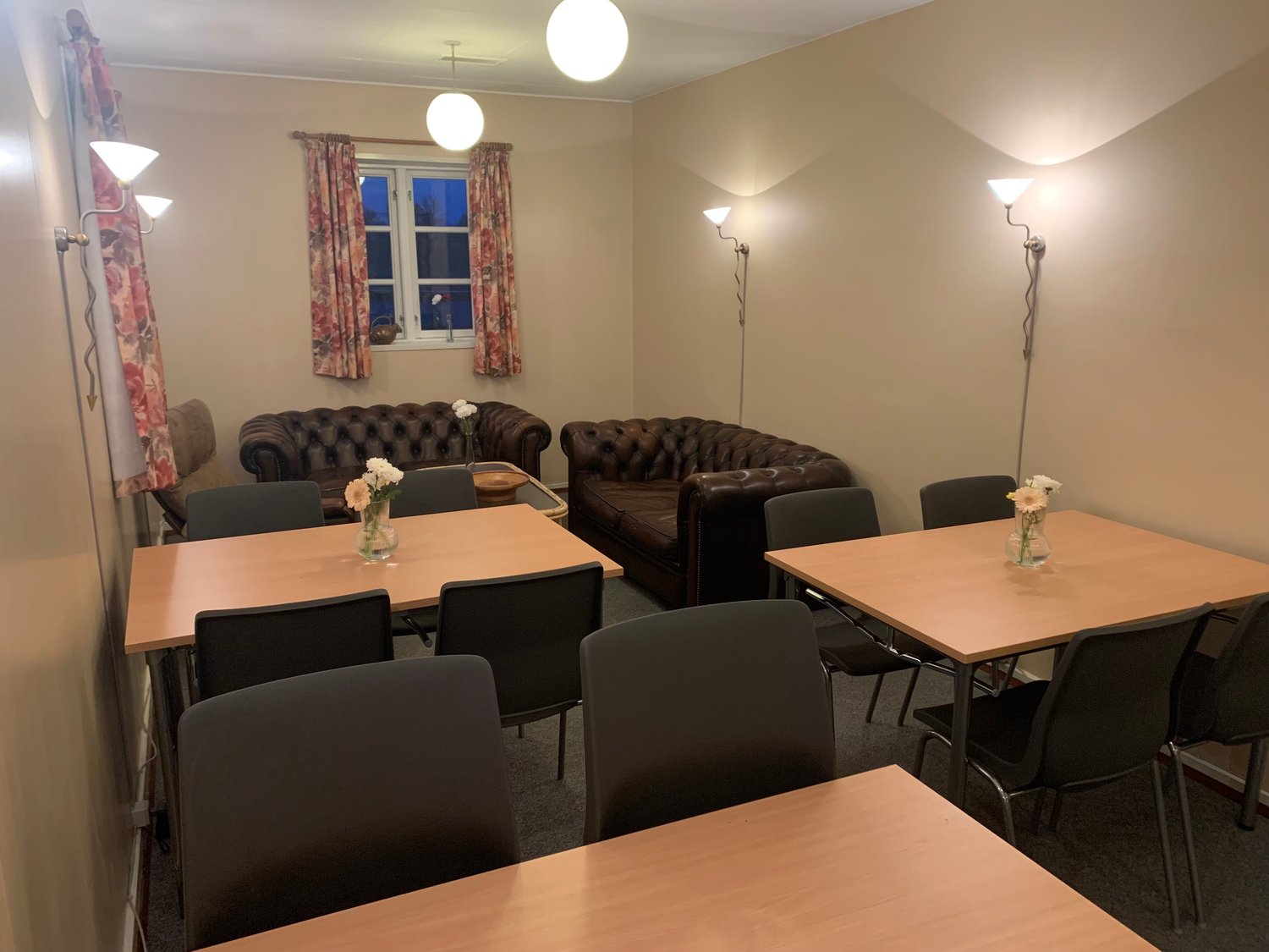 Hyggekrog med chesterfield-sofaer og blomster på bordene